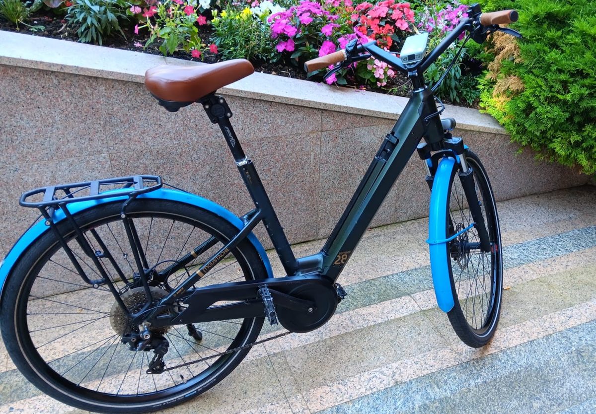 Vélo électrique de ville noir avec garde-boue bleus et selle marron